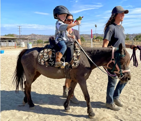 Two teachers from TTRC helping a kid to ride a horse